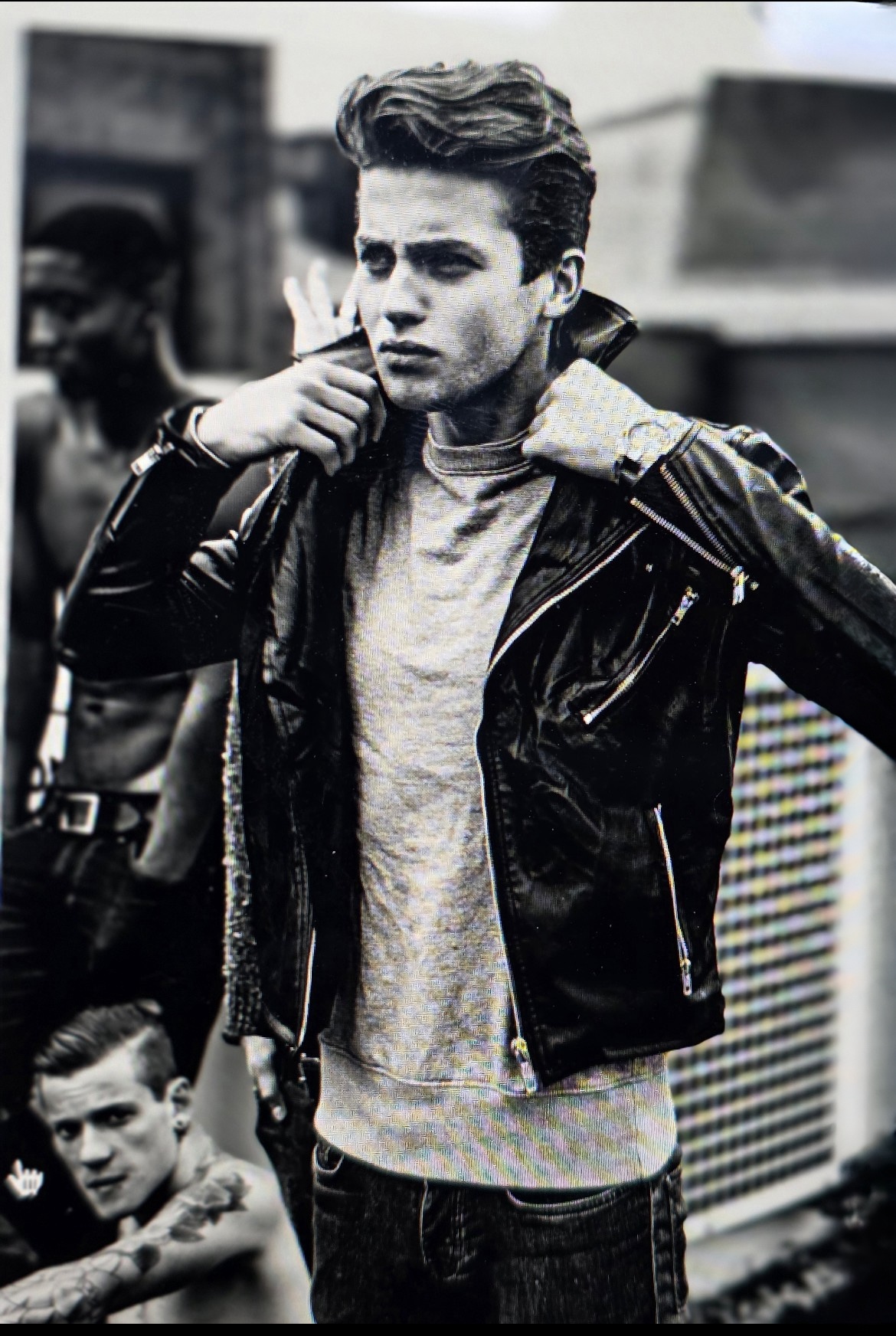 black and white photograph of a caucasian handsome young man wearing a stylish leather biker jacket over a t-shirt with dark hair