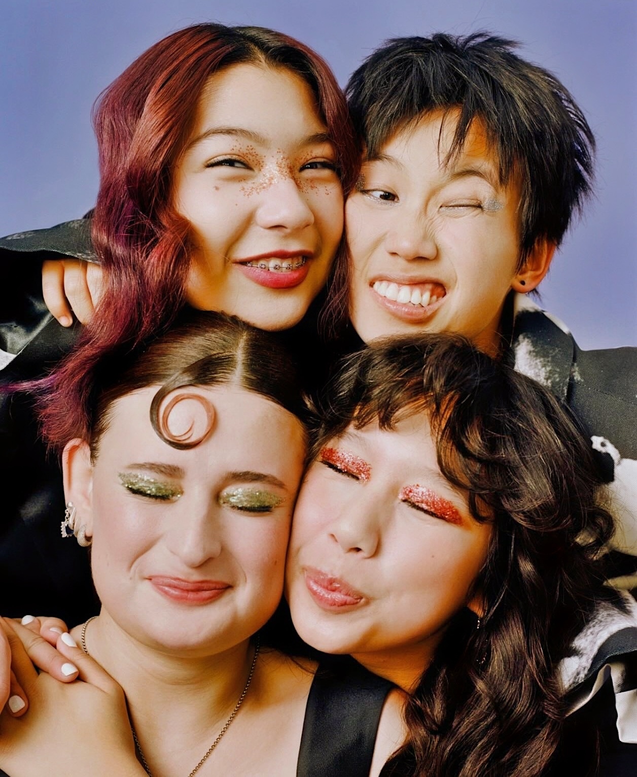 Color photograph of the four female band members of the music group Linda Lindas facing the camera making funny faces, smiling