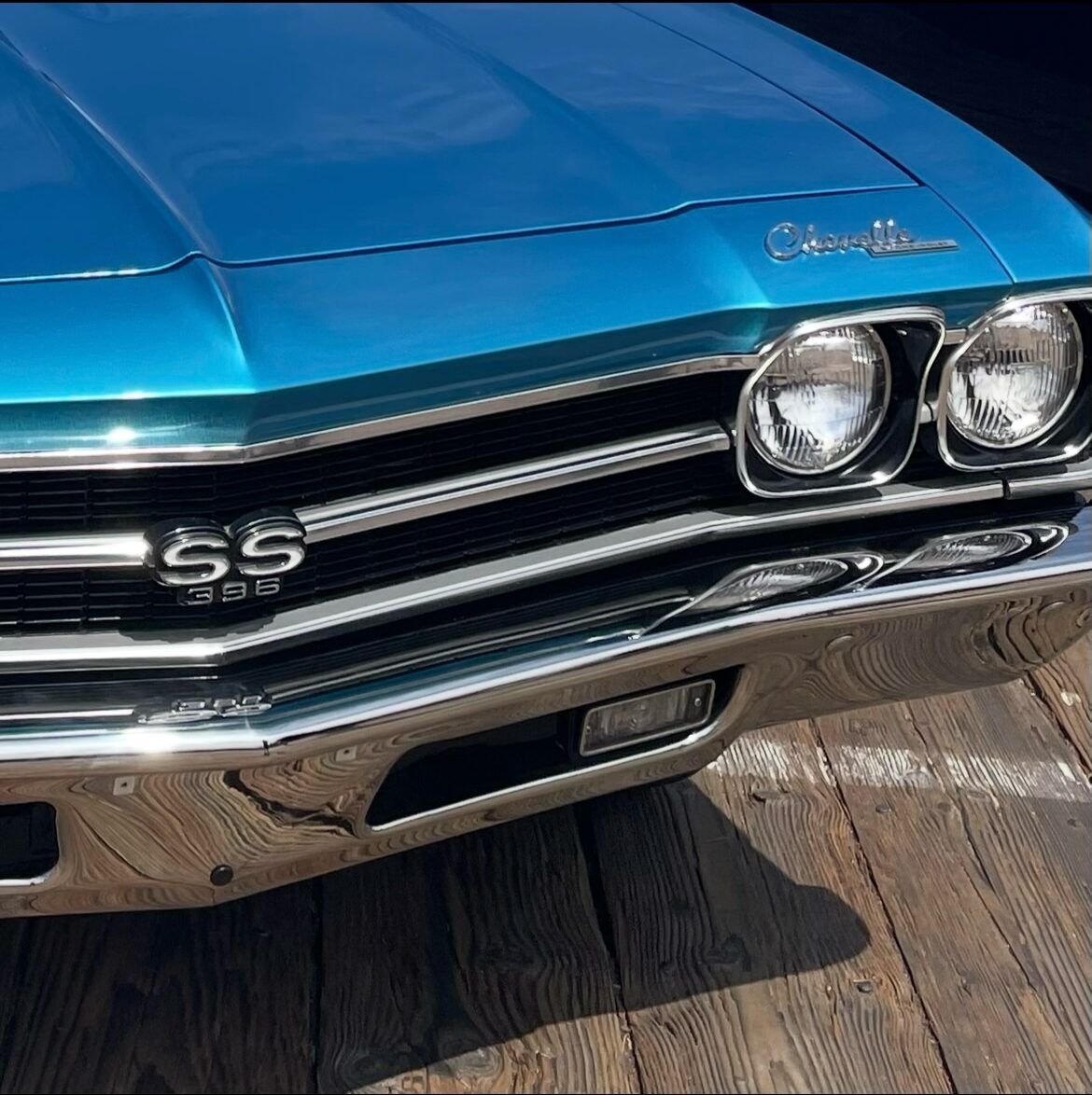Color photograph of a blue vintage car focused on the front chrome details of the vehicle